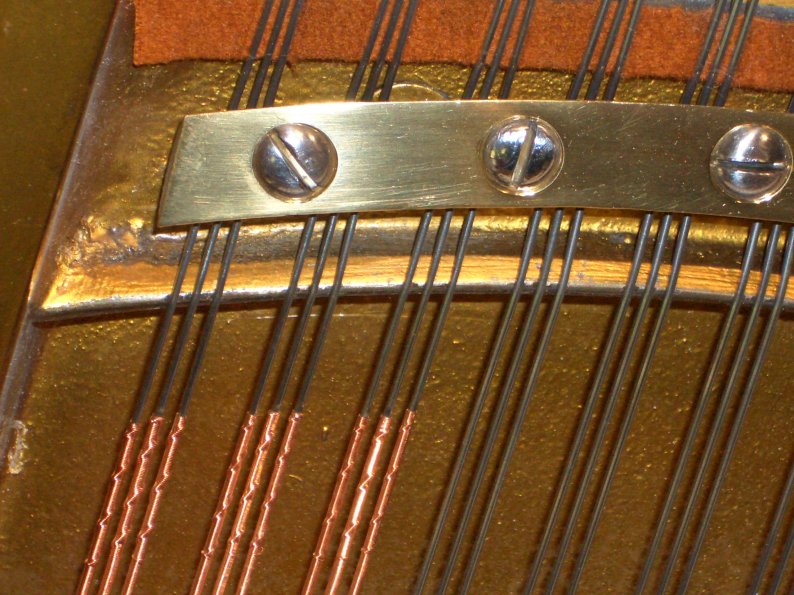 tri-chords on an upright piano showing precise copper line